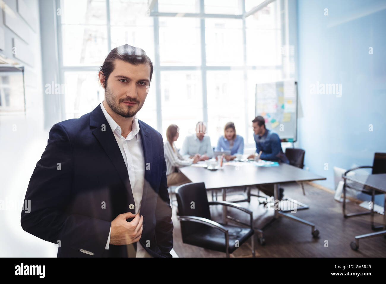 Imprenditore fiducioso in piedi contro i colleghi Foto Stock