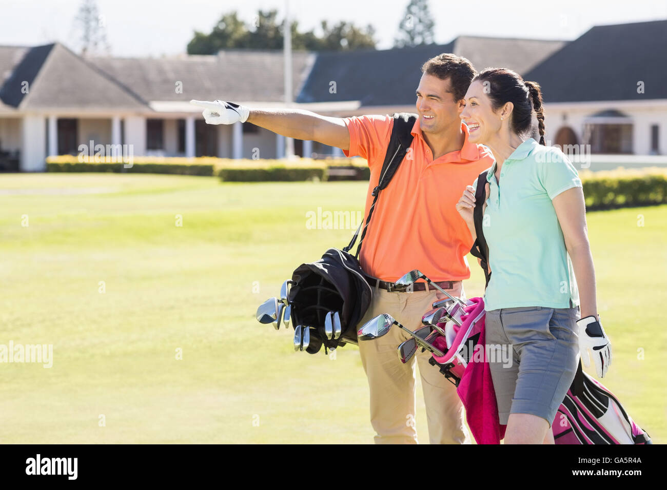 Un uomo indica mentre si cammina da donna che trasportano borsa da golf Foto Stock