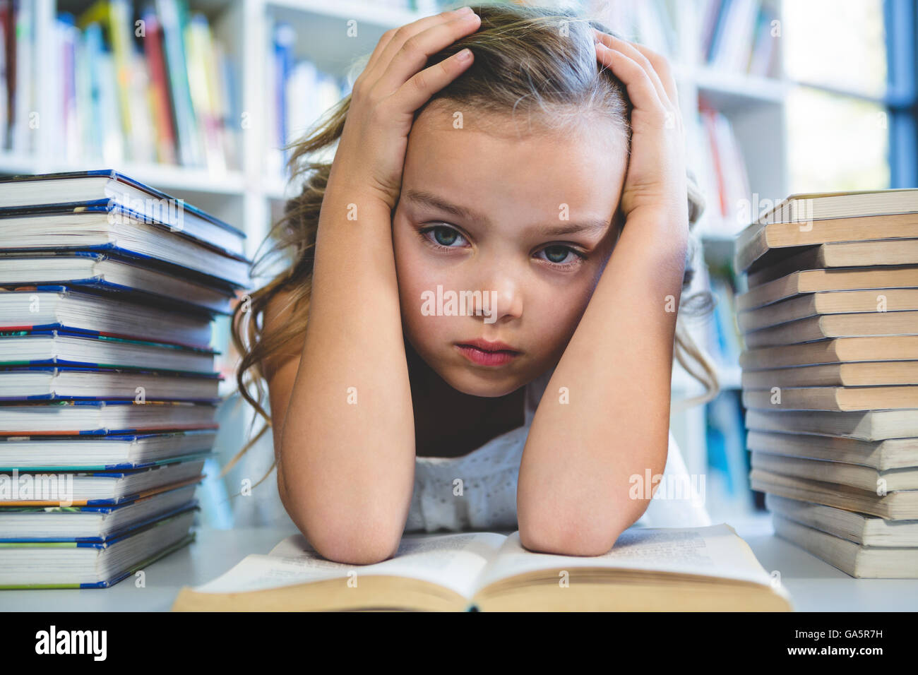 Ha sottolineato la ragazza con testa in mano alla biblioteca della scuola Foto Stock