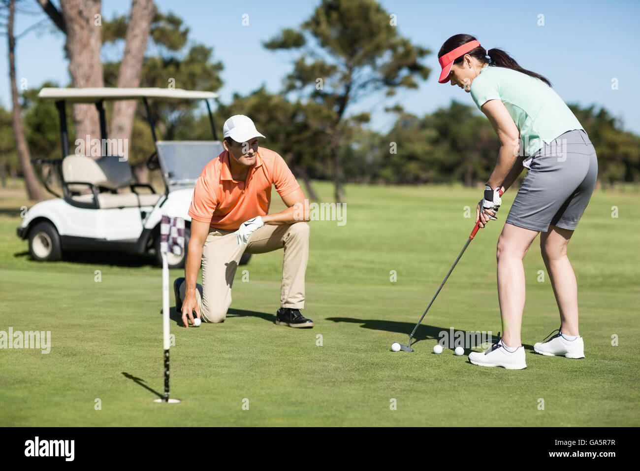 Donna giocando a golf mentre in piedi da uomo Foto Stock