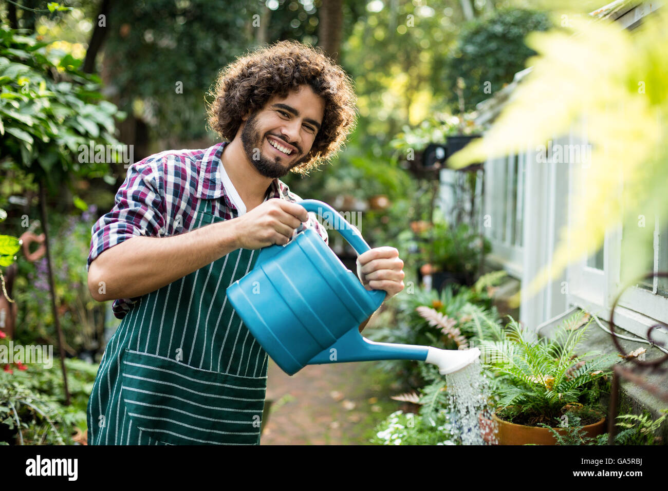 Fiducioso maschio irrigazione giardiniere piante in vaso Foto Stock