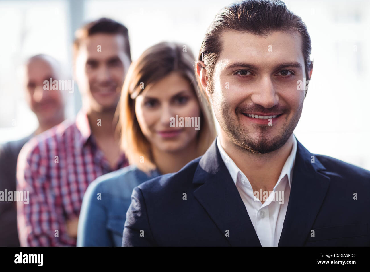 Imprenditore sorridente con i colleghi in piedi in fila Foto Stock
