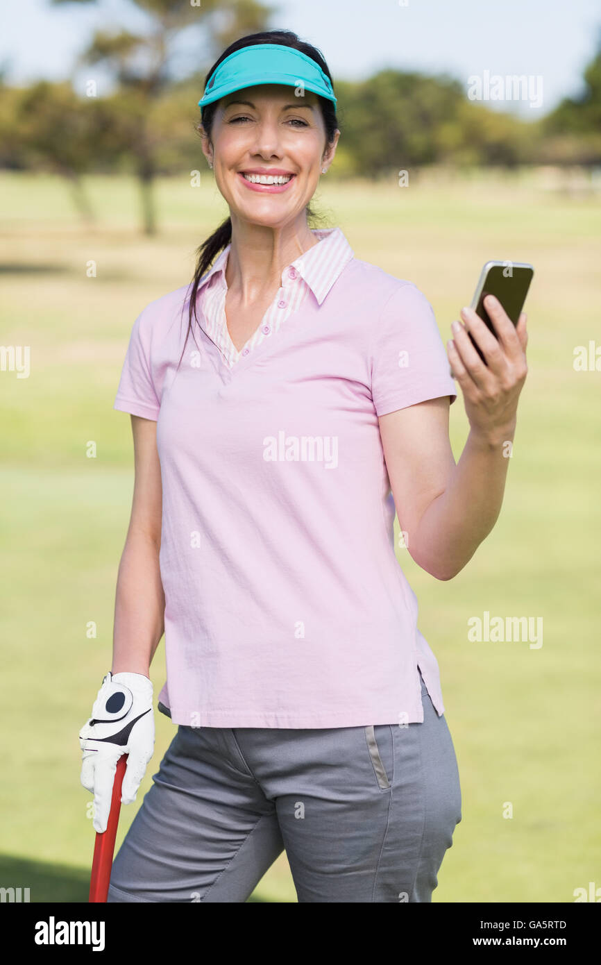 Ritratto di sorridere golfista donna usando il telefono Foto Stock