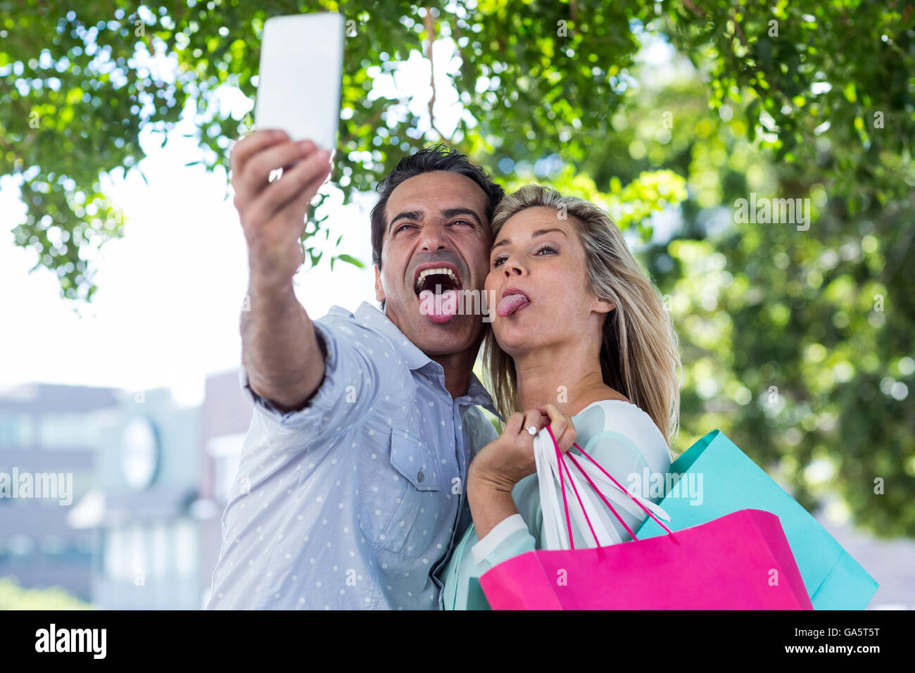 Coppia costituente la faccia tenendo selfie Foto Stock