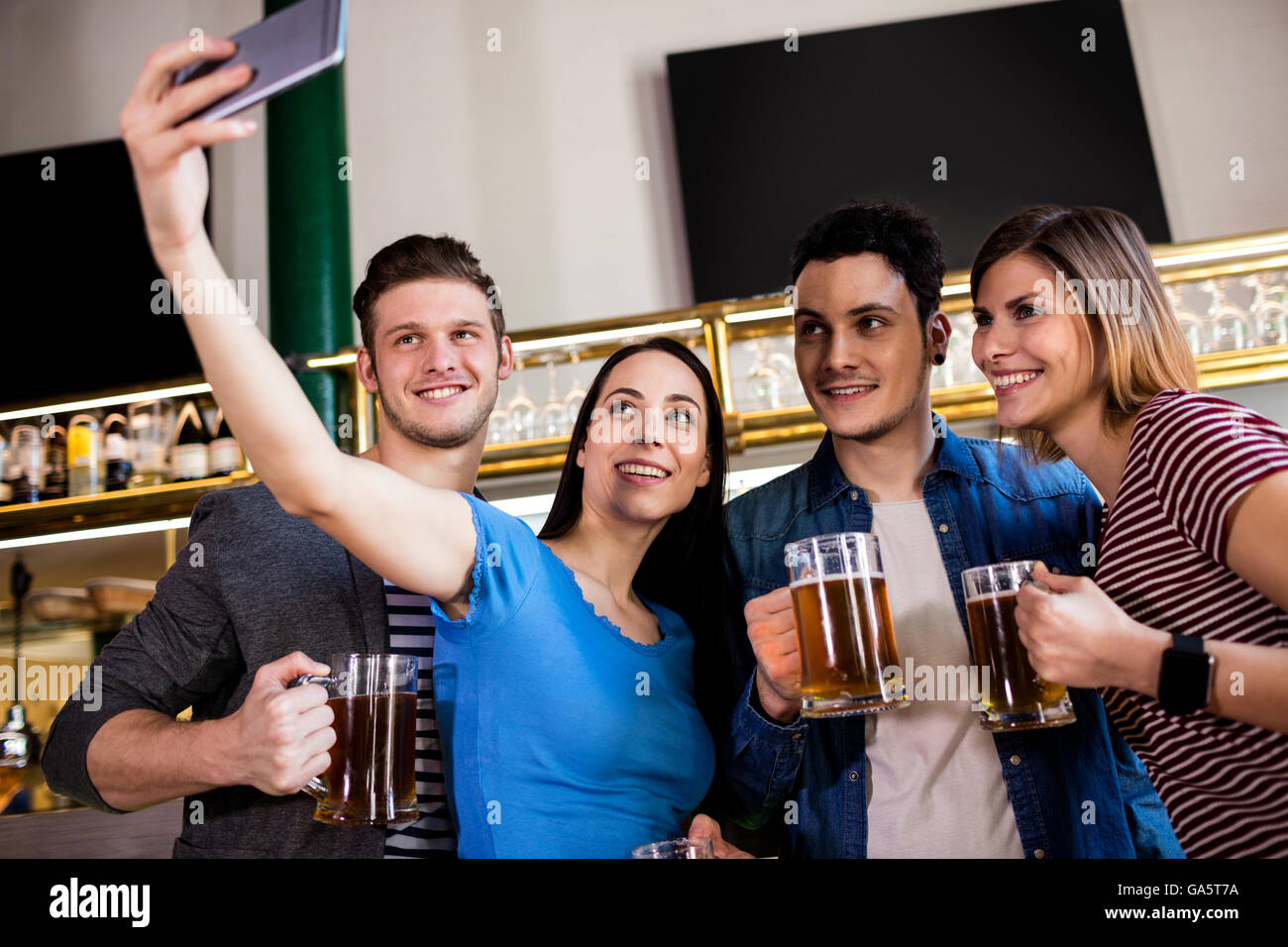Giovani amici prendendo selfie tenendo boccale di birra Foto Stock