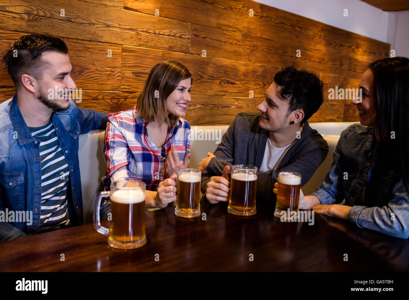 Amici con boccali da birra al tavolo nel ristorante Foto Stock