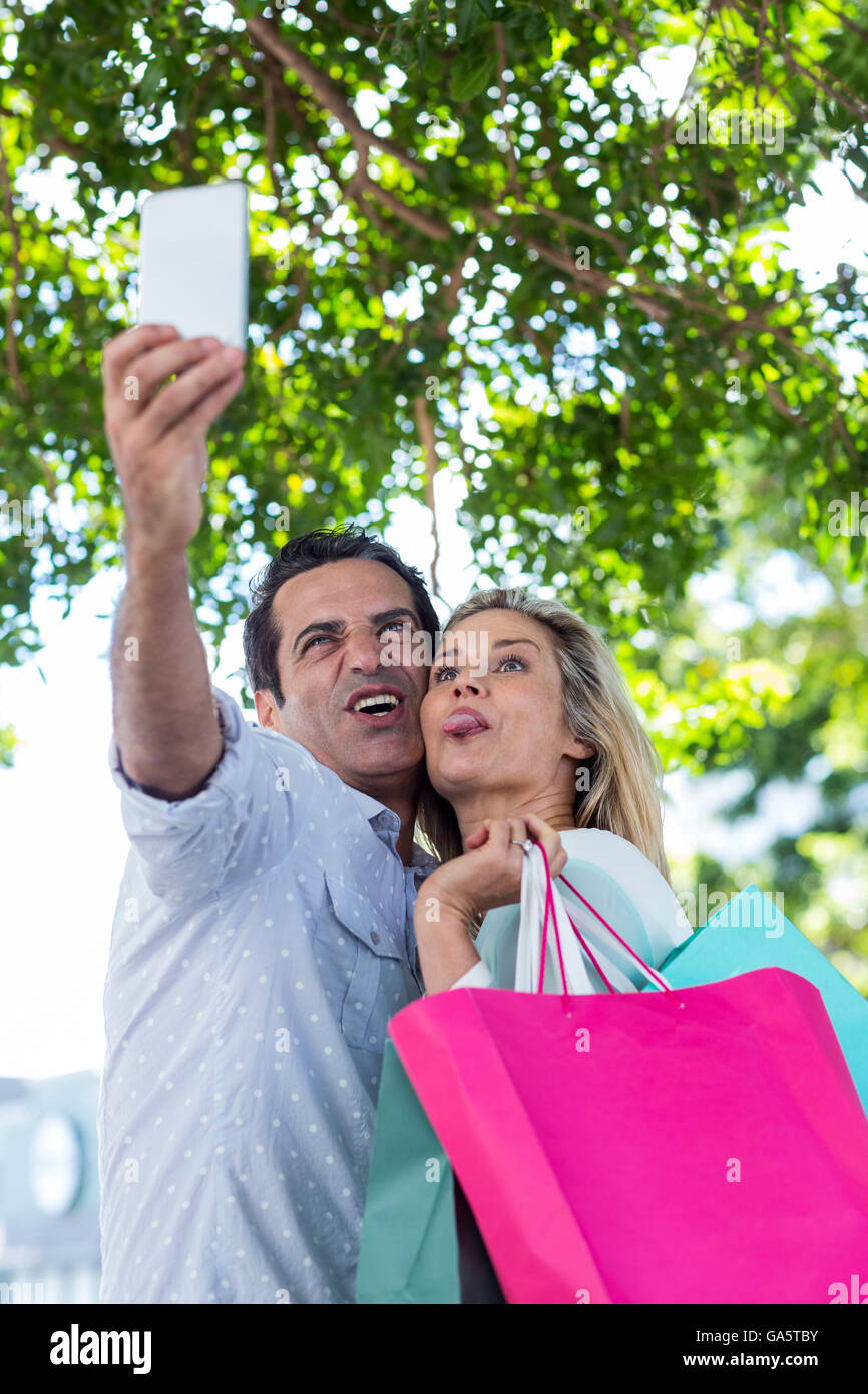 Coppia costituente la faccia tenendo selfie in città Foto Stock