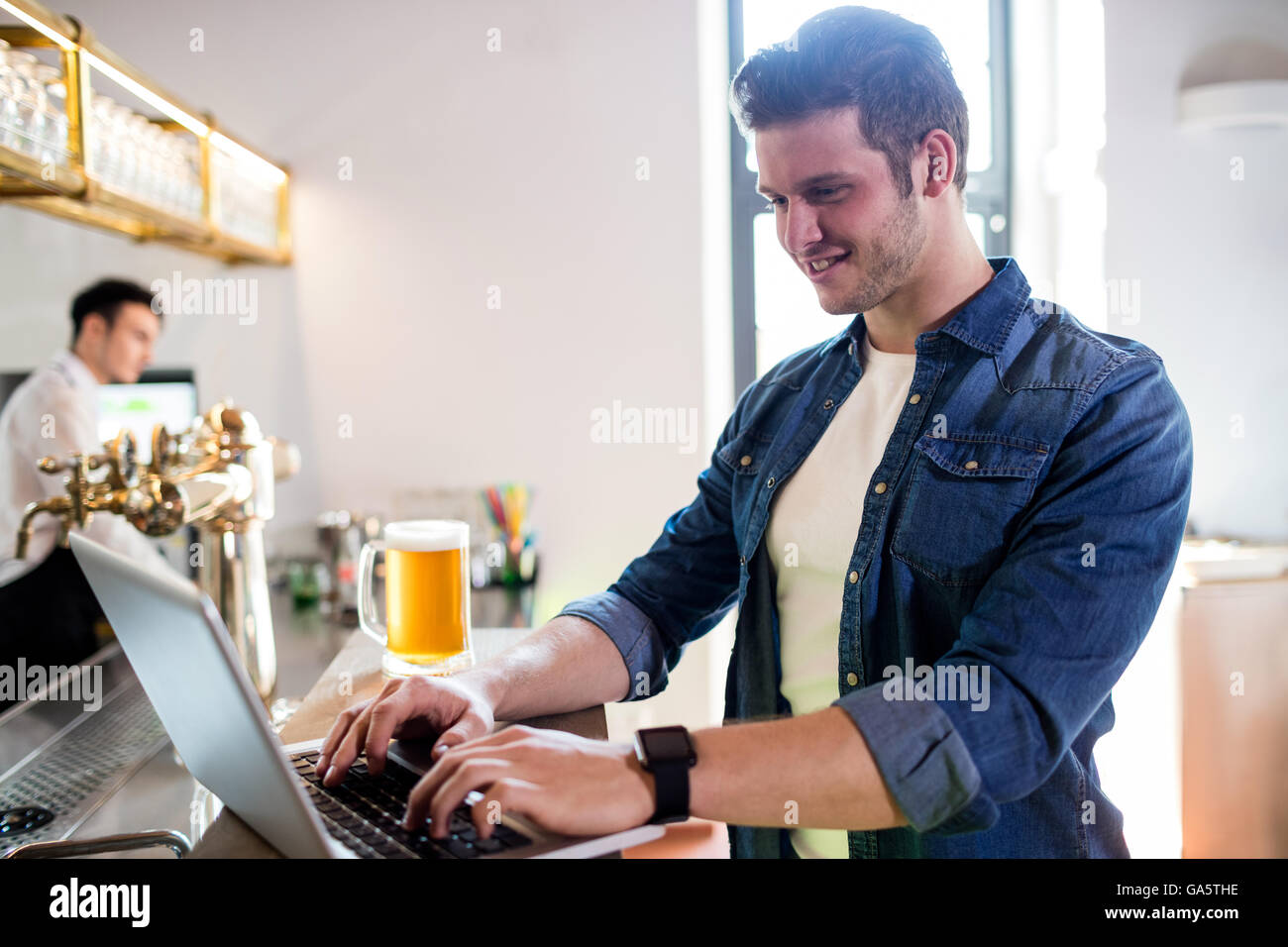 Giovane uomo utilizzando computer portatile presso il contatore Foto Stock