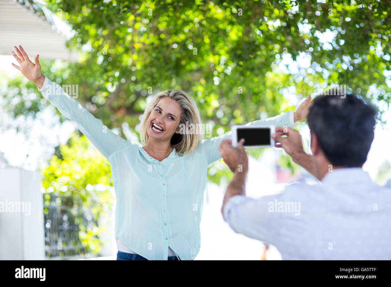 Uomo di fotografare Allegra donna contro alberi Foto Stock