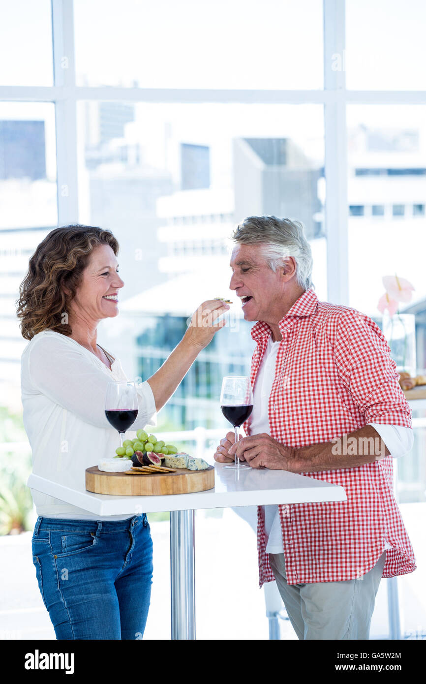 Donna sorridente di alimentazione per alimentare l'uomo Foto Stock