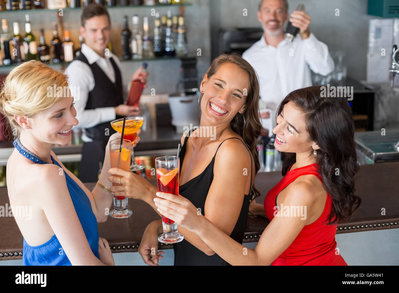 Happy amici di sesso femminile tenendo un bicchiere di cocktail al bancone bar Foto Stock