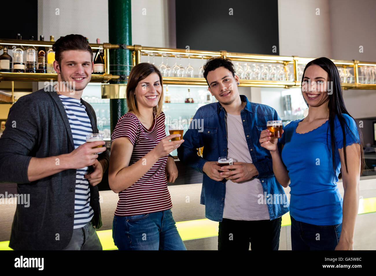 Gli amici di sorridere mentre si tiene la birra di vetro al contatore Foto Stock