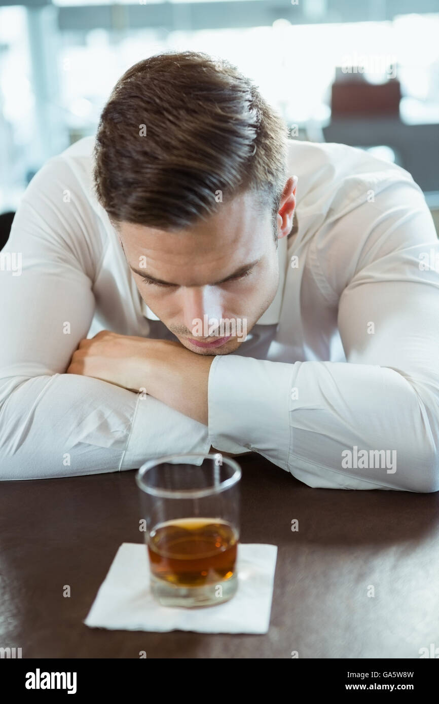 Premuto un uomo guarda il vetro di alcool Foto Stock