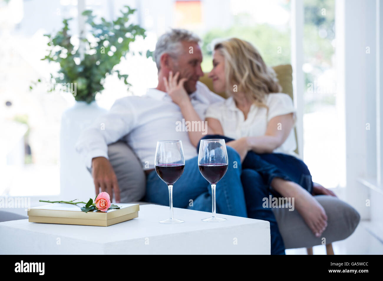 Coppia romantica seduti sulla poltrona con il vino e la confezione regalo Foto Stock