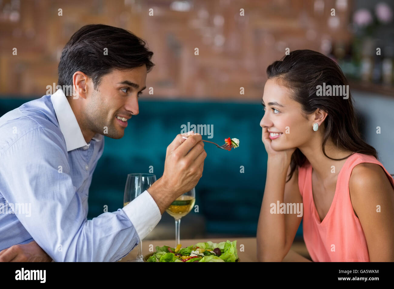 Uomo sorridente pasto di alimentazione per donna Foto Stock