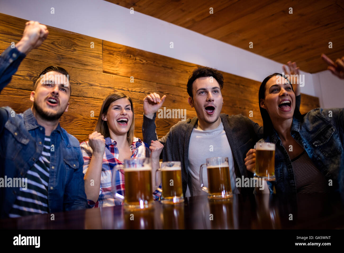 Gli amici sorseggiando con boccali da birra nel ristorante Foto Stock