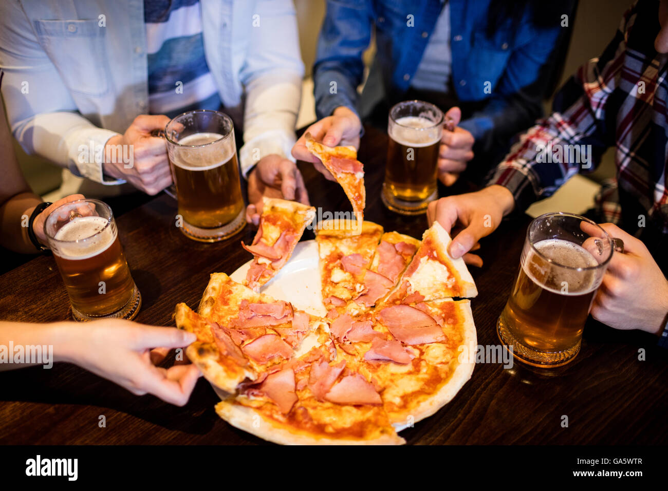 Amici con boccale di birra e pizza al bar Foto Stock