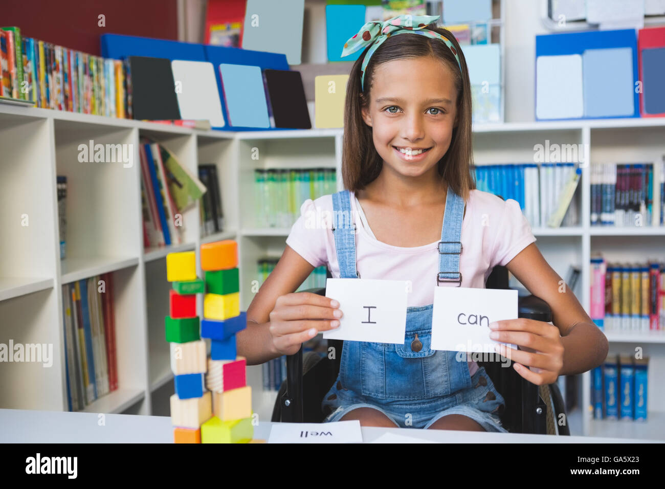 Ragazza di disabili che mostra sulla targhetta che legge posso in libreria Foto Stock