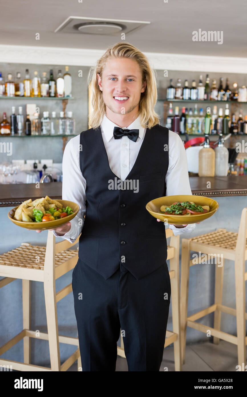 Cameriere placcato in azienda i pasti nel ristorante Foto Stock