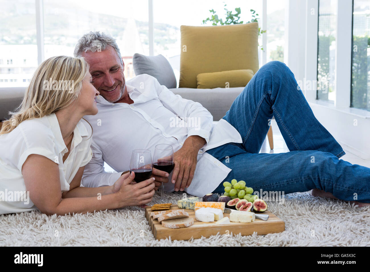 Coppia romantica con il vino rosso e il cibo mentre giaceva sul tappeto Foto Stock