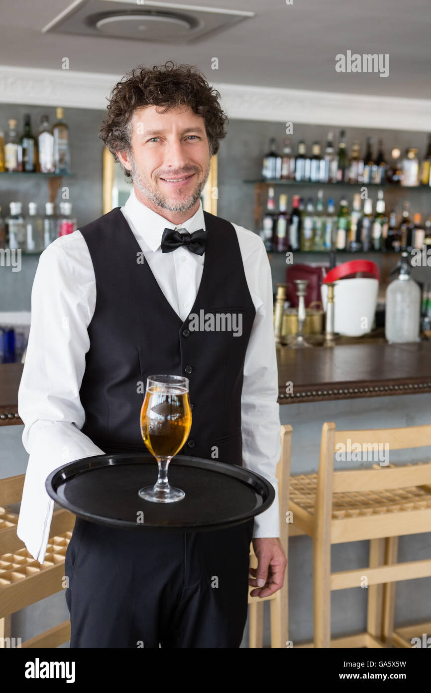 Cameriere tenendo un vassoio con un bicchiere di birra Foto Stock