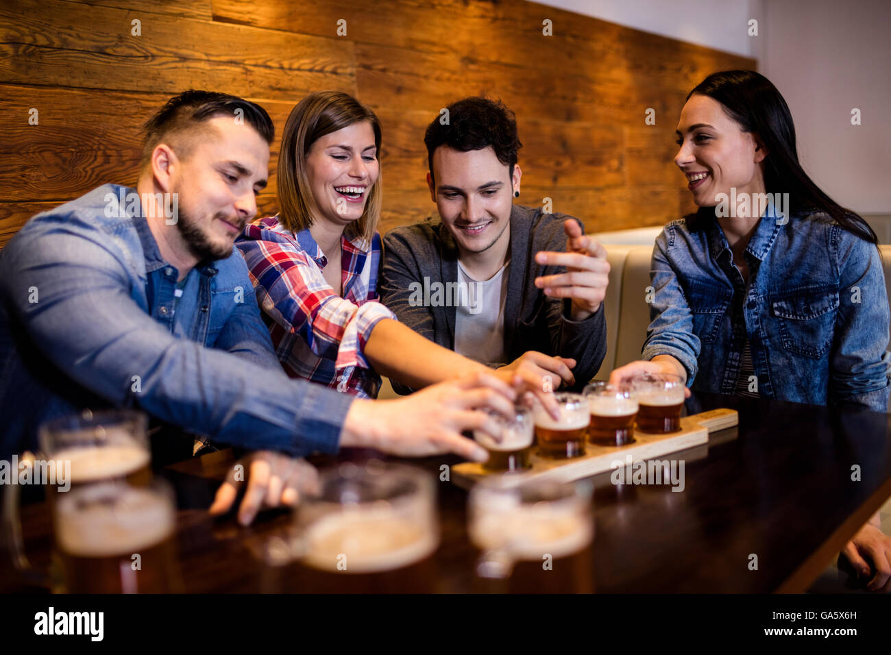 Gli amici sorseggiando la birra a tavola Foto Stock