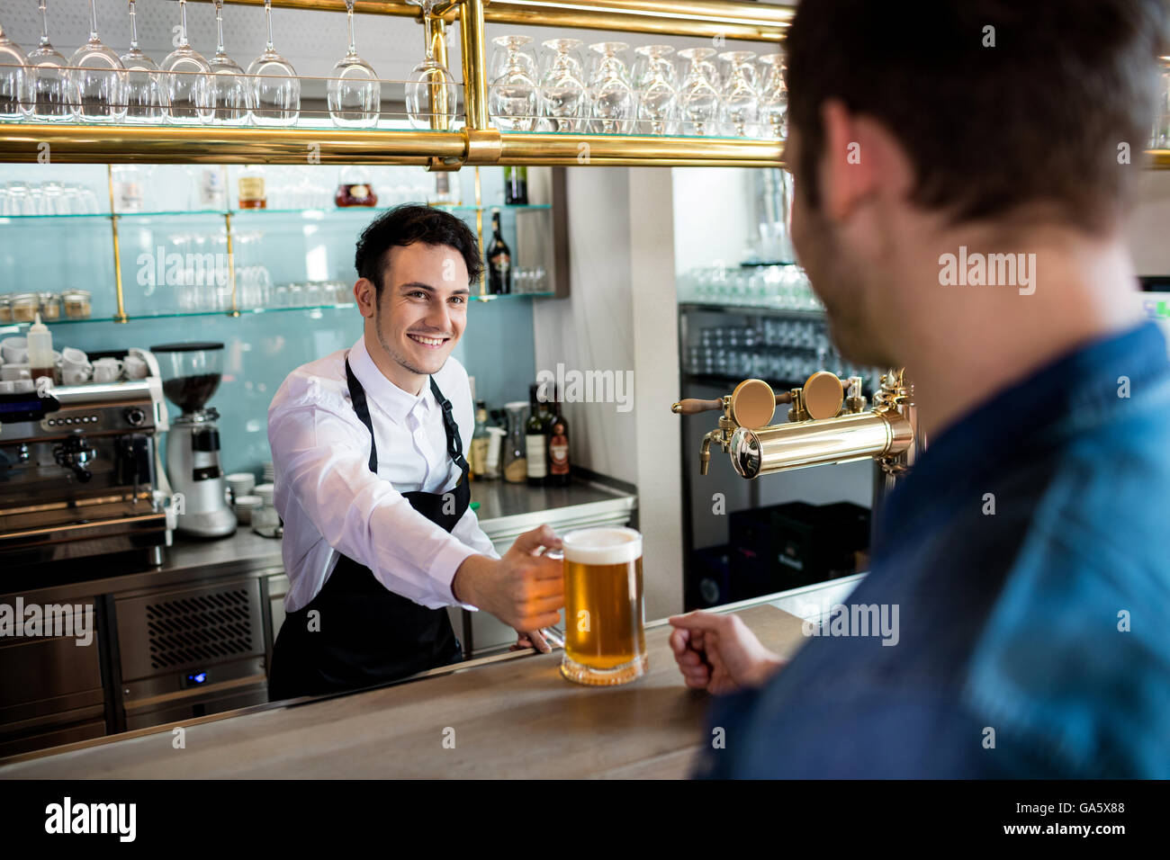 Il barista che serve birra al cliente maschio Foto Stock