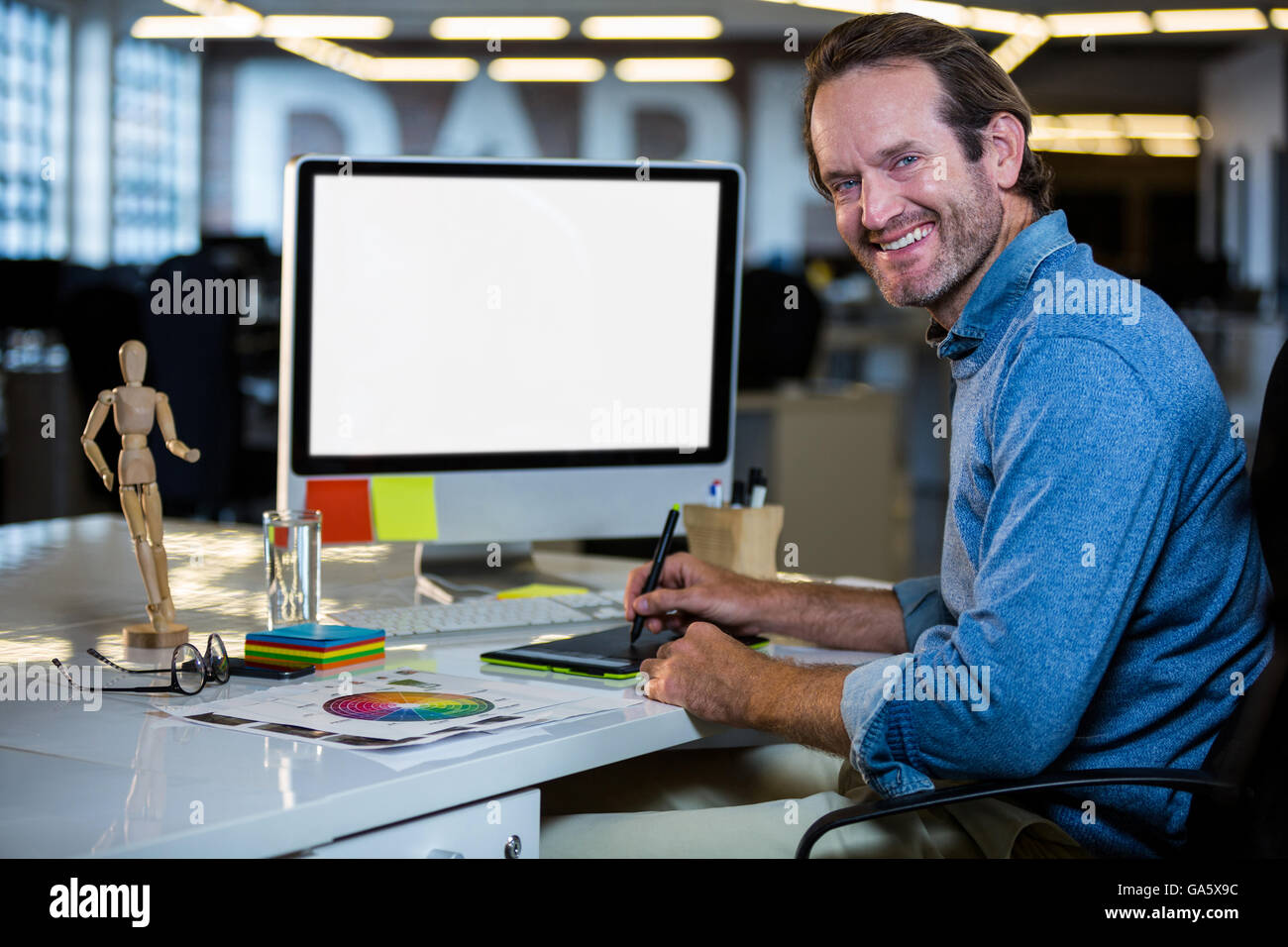 Editor foto sorridente mentre si lavora su una tavoletta grafica Foto Stock