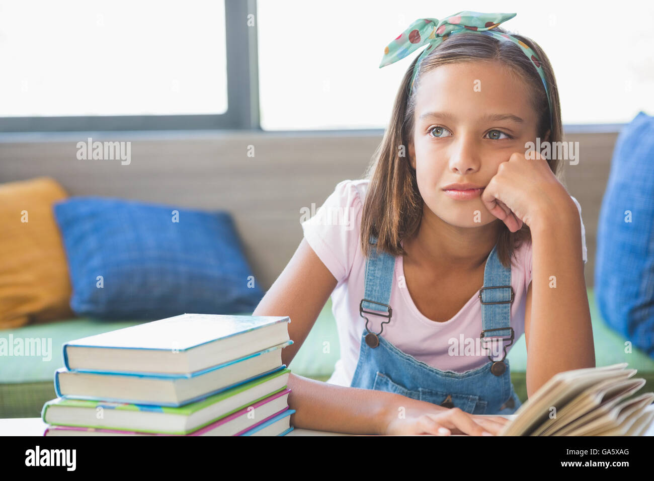 Schoolgirl seduto sul tavolo e la lettura di libro in biblioteca Foto Stock