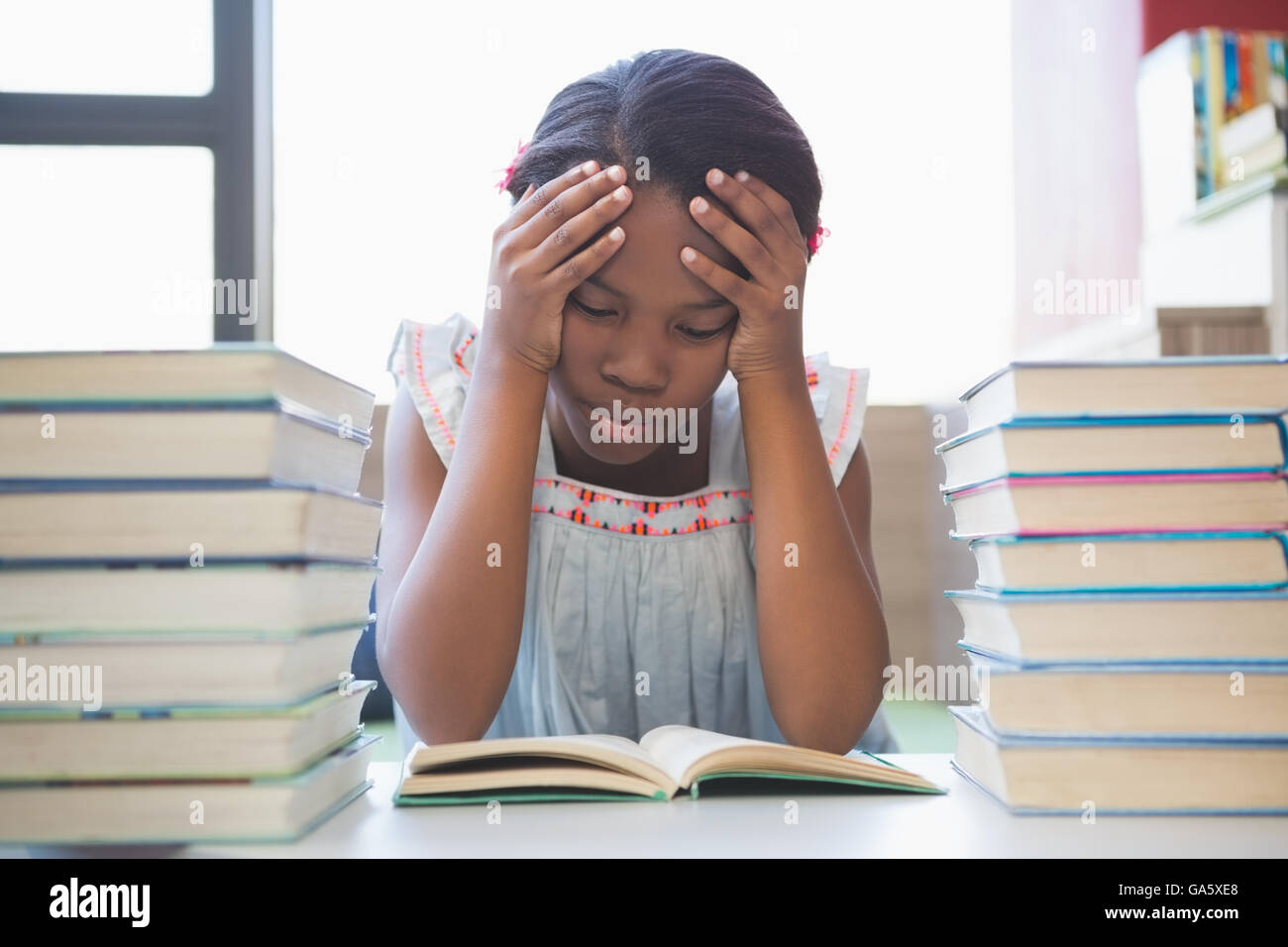 School girl leggendo un libro in biblioteca Foto Stock