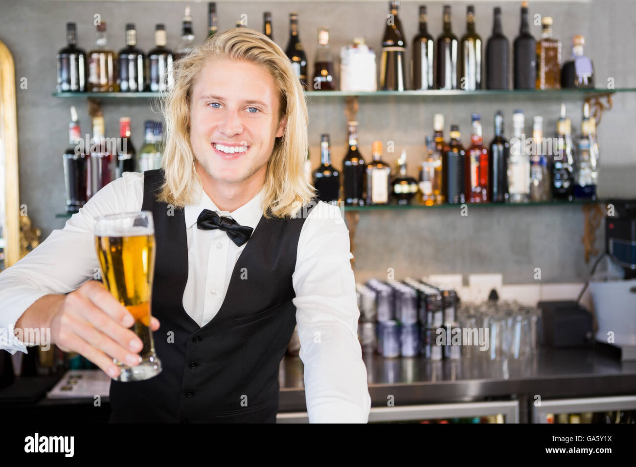 Cameriere tenendo un bicchiere di birra al bar counter Foto Stock