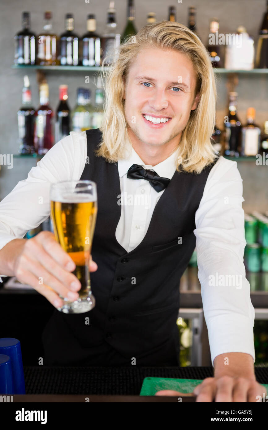 Cameriere tenendo un bicchiere di birra al bar counter Foto Stock