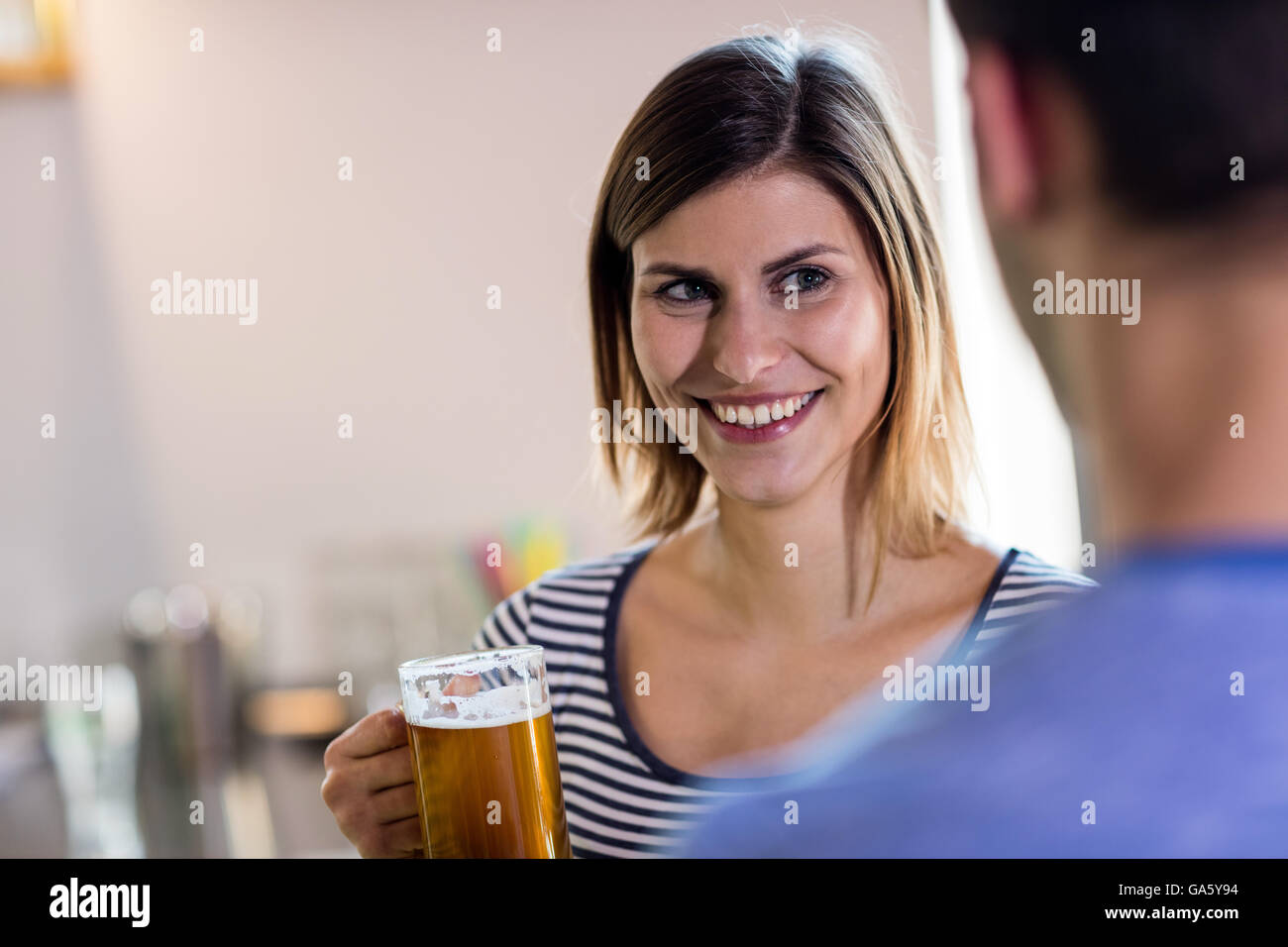 Donna che guarda al ragazzo mentre beve birra Foto Stock