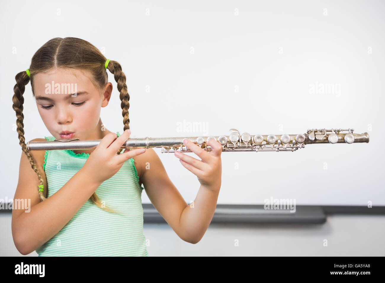 Schoolgirl riproduzione di flauto in aula Foto Stock