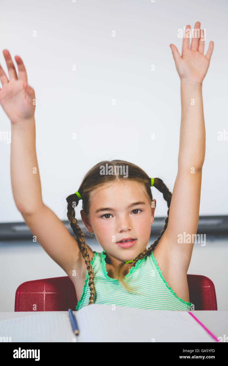 Ritratto di schoolgirl alzando le braccia in aula Foto Stock