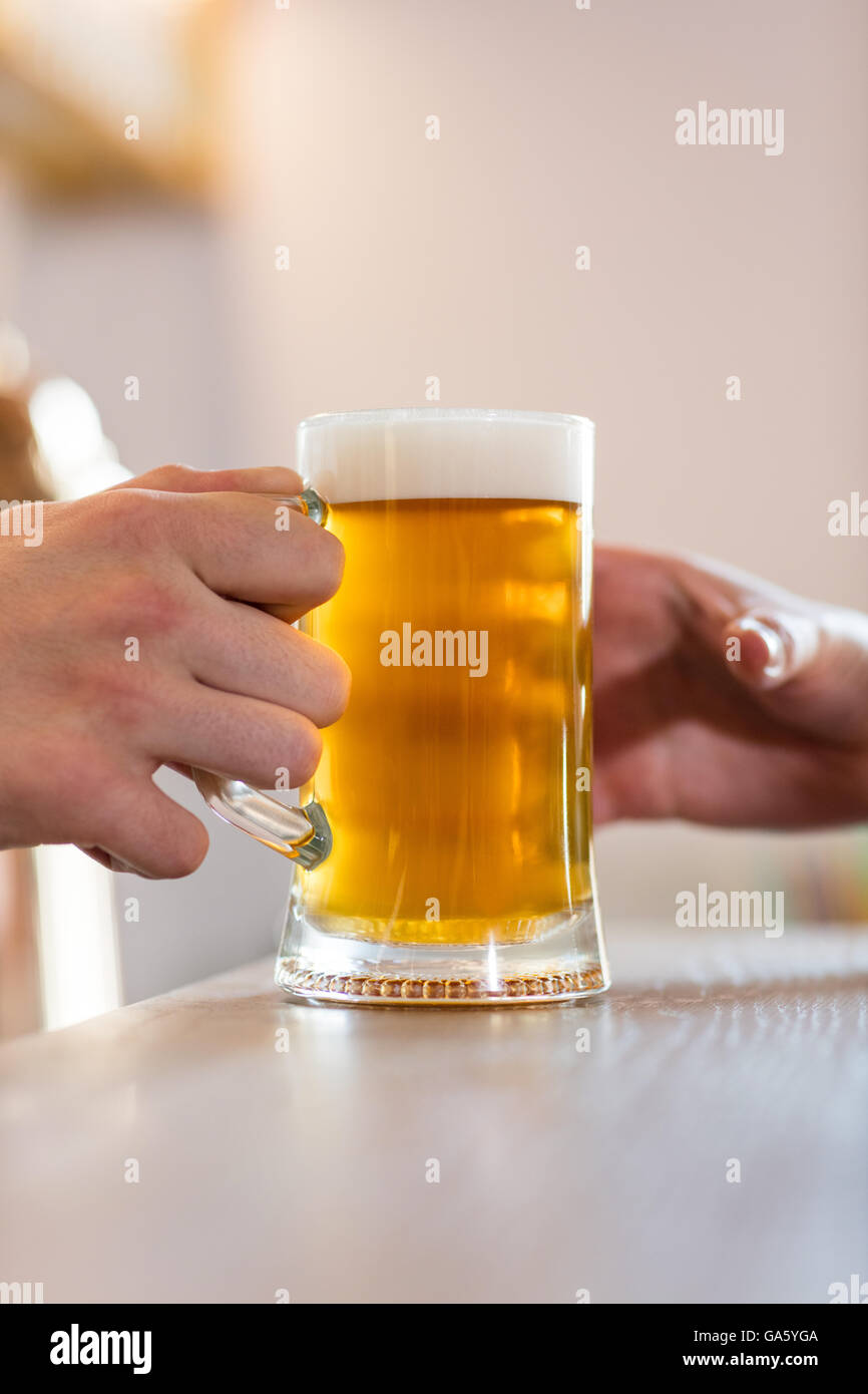 Il barista che serve birra al cliente al bancone bar Foto Stock
