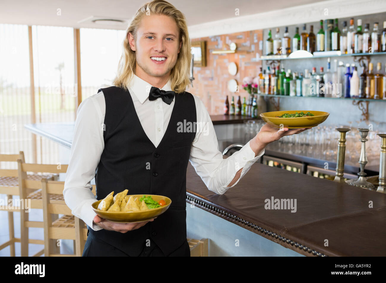 Cameriere placcato in azienda i pasti nel ristorante Foto Stock