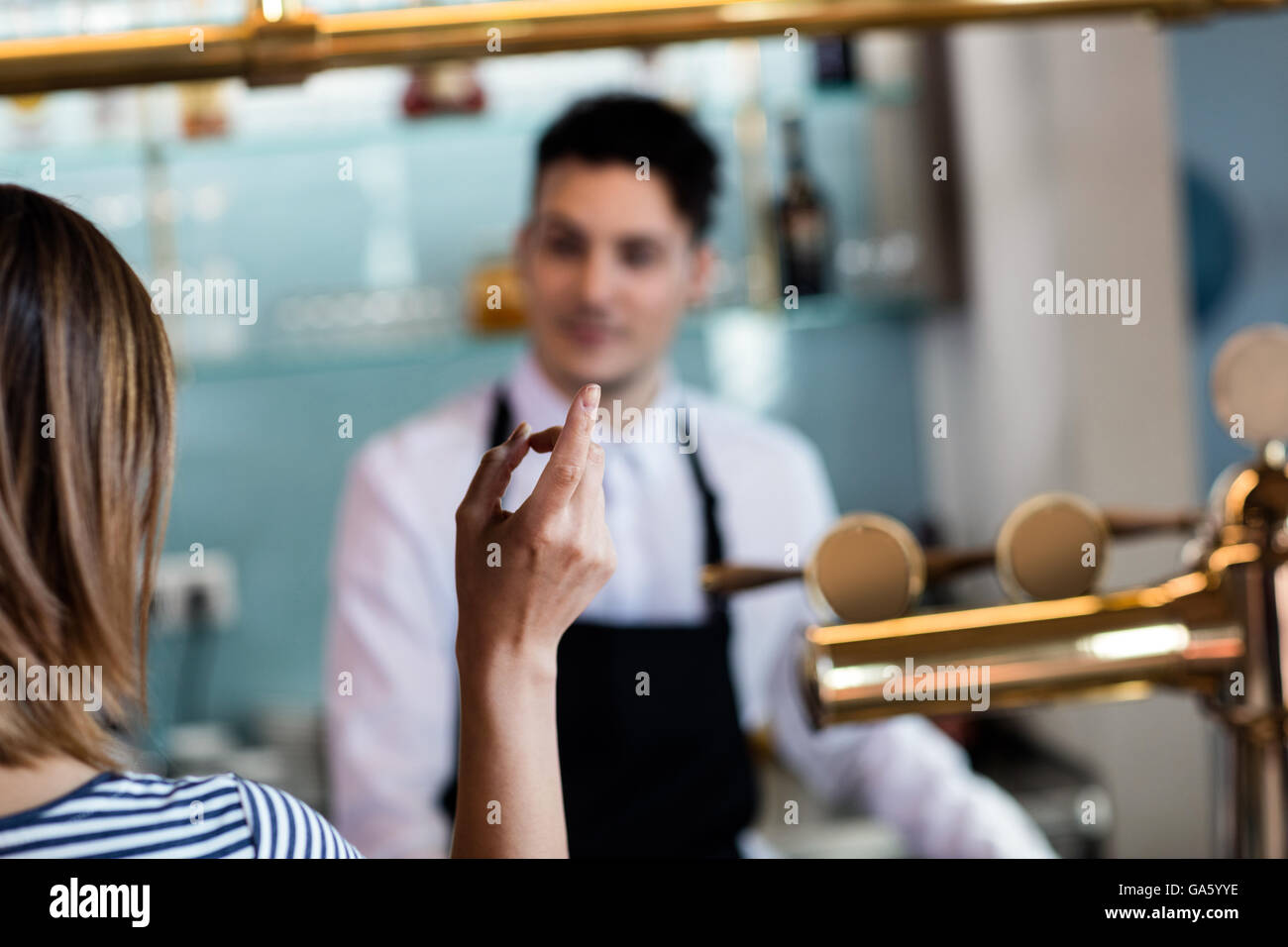Donna gesticolando mentre si parla con il barista Foto Stock