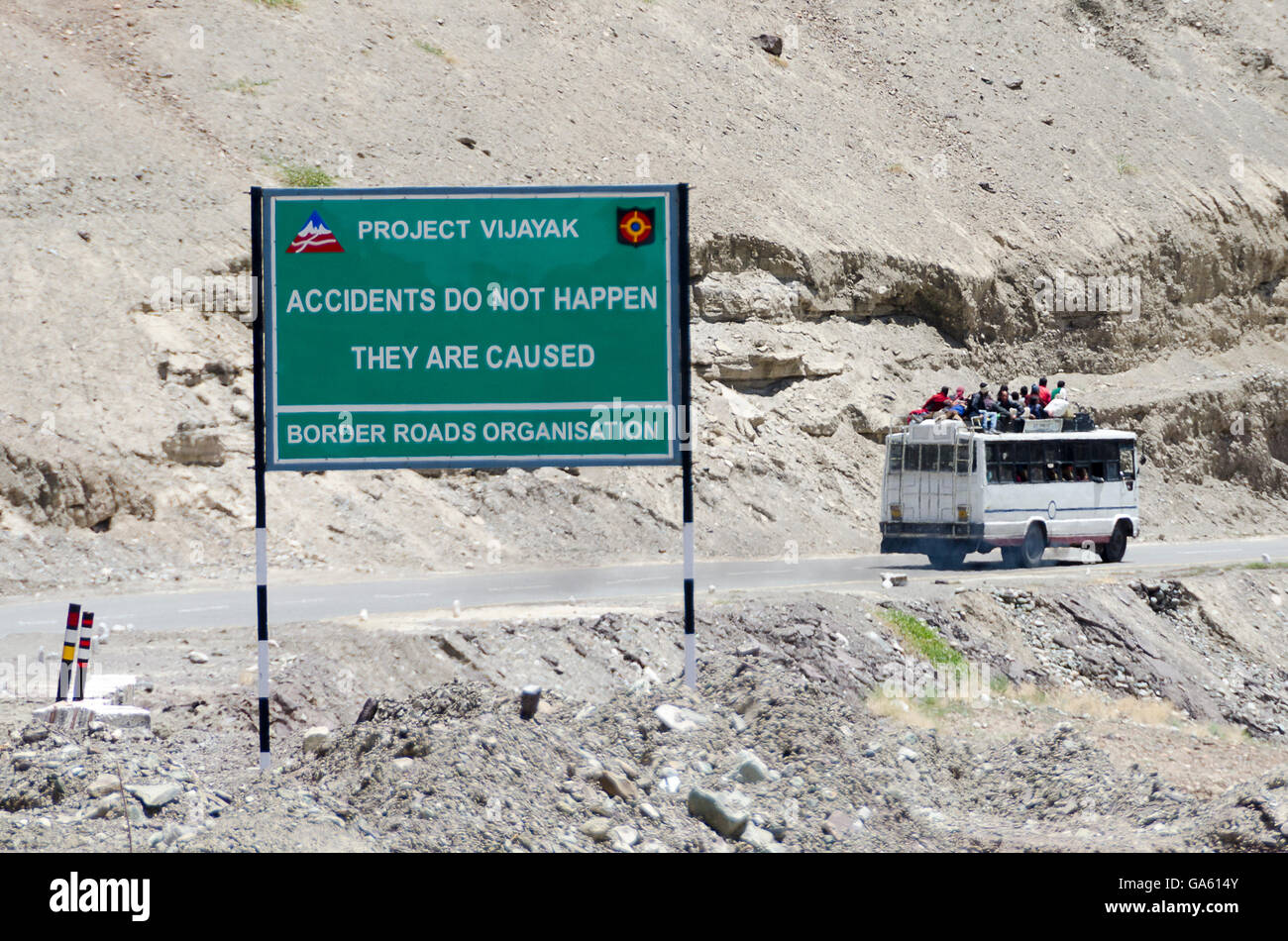 Bus con persone sul tetto passando la sicurezza stradale segno su Leh a Srinagar Road, Ladakh, Jammu e Kashmir in India. Foto Stock