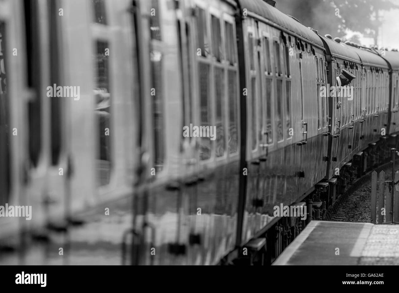 Un treno a vapore tirando fuori della piattaforma con una guardia guardando fuori dalla finestra Foto Stock