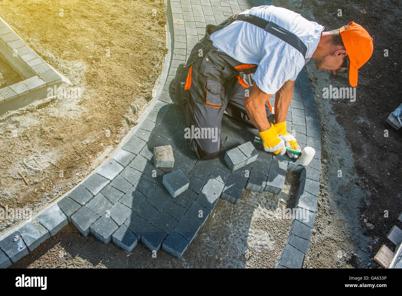 Mattone opere di pavimentazione. Professionale lavoratore caucasica Building Block Hardstanding lastricato sentiero Foto Stock