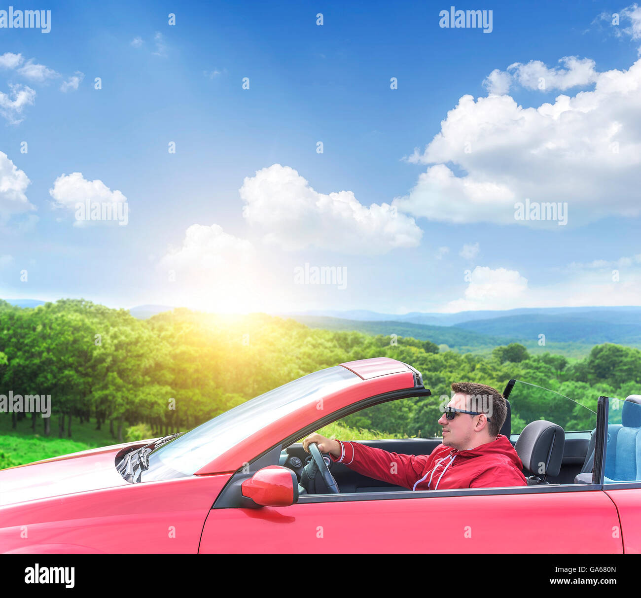 Uomo alla guida di una vettura convertibile sulla strada del paese dalla foresta. Foto Stock
