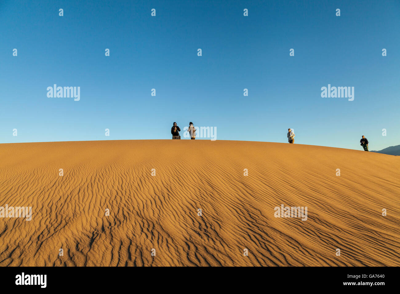 I turisti sulla cima di una duna di sabbia a Mesquite dune di sabbia nel Parco Nazionale della Valle della Morte, CALIFORNIA, STATI UNITI D'AMERICA Foto Stock