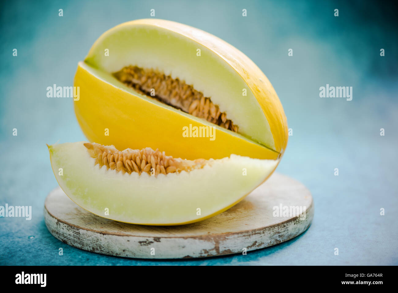 Intero e tagliare a fette di melone Honeydew su legno scheda rustico Foto Stock
