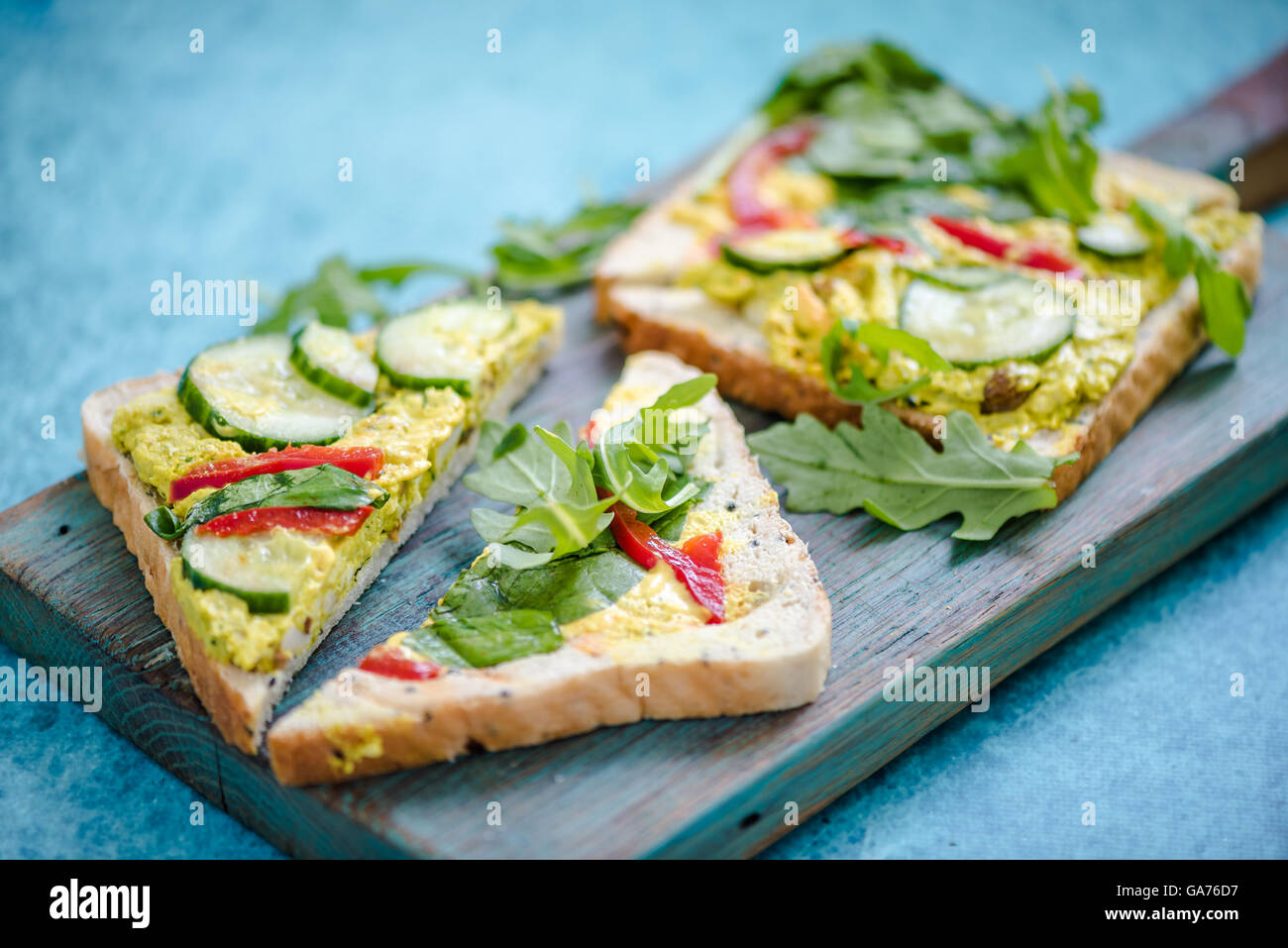 Triangolo di pane con pollo e rucola su legno scheda rustico Foto Stock