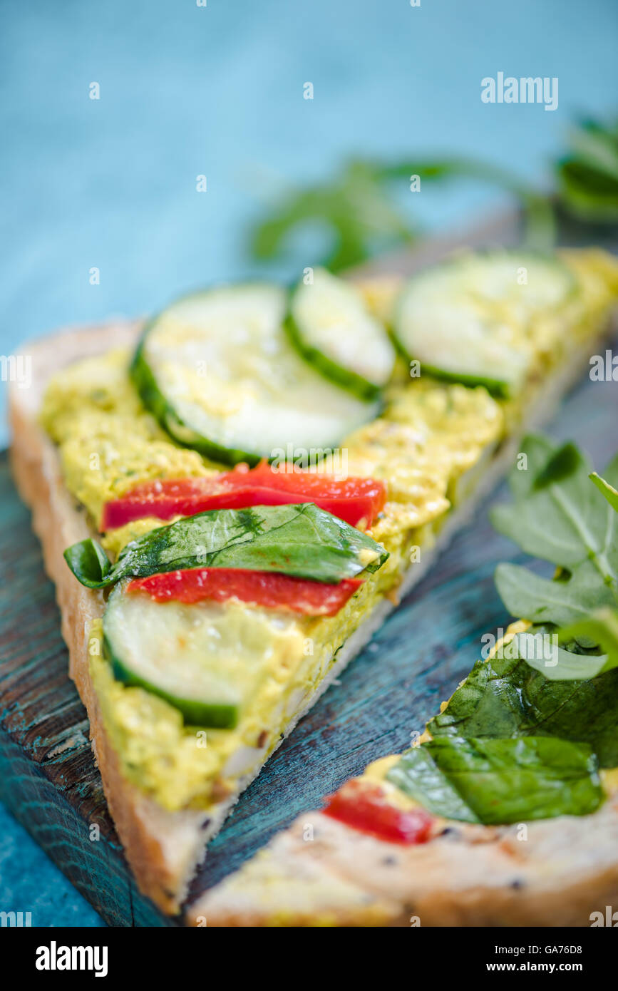 Triangolo di pane con pollo e rucola su legno scheda rustico Foto Stock