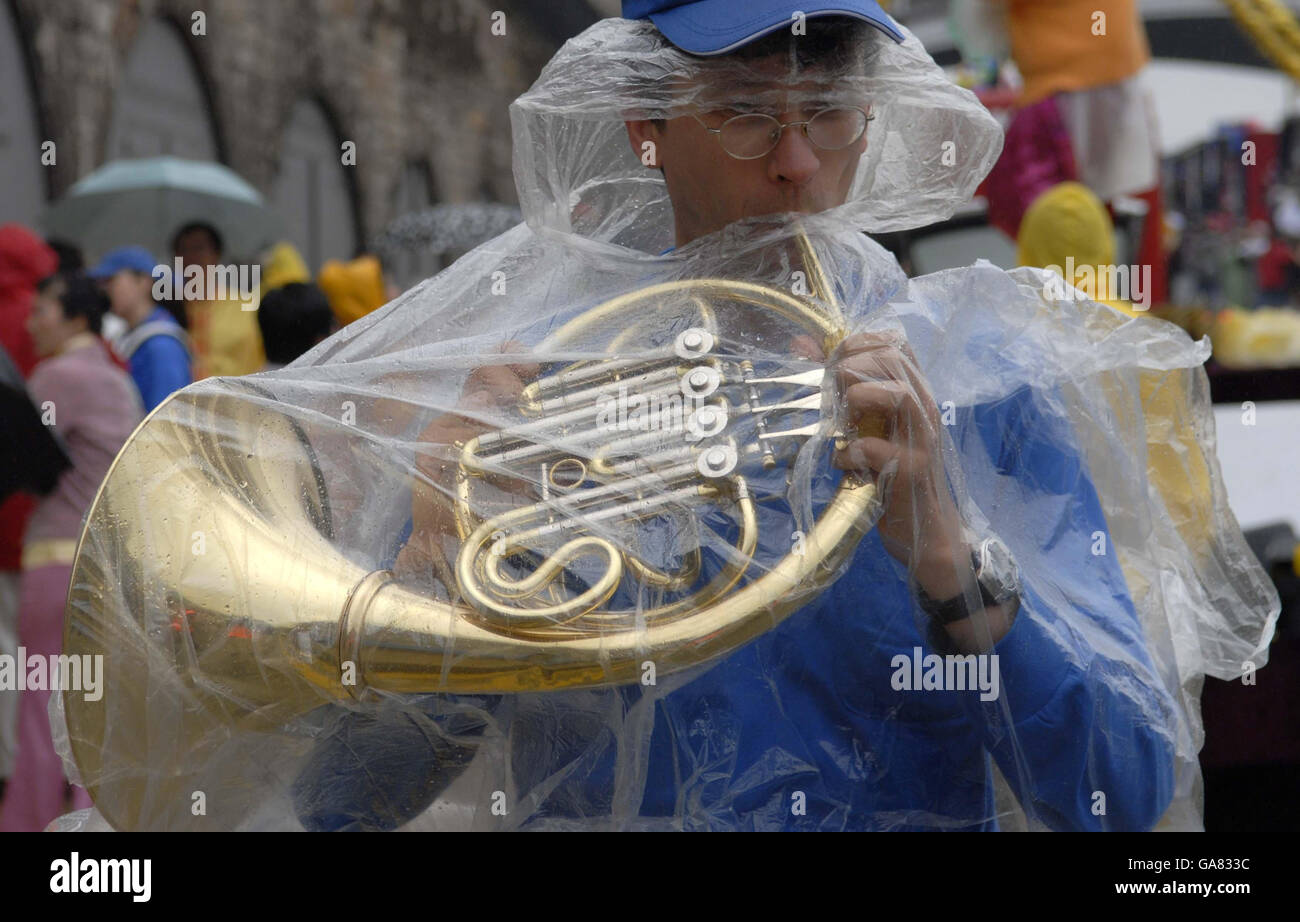 Un uomo affronta la pioggia mentre suona un corno francese, mentre l'annuale Edinburgh Festival Cavalcade si fa strada attraverso le strade della capitale scozzese. Foto Stock
