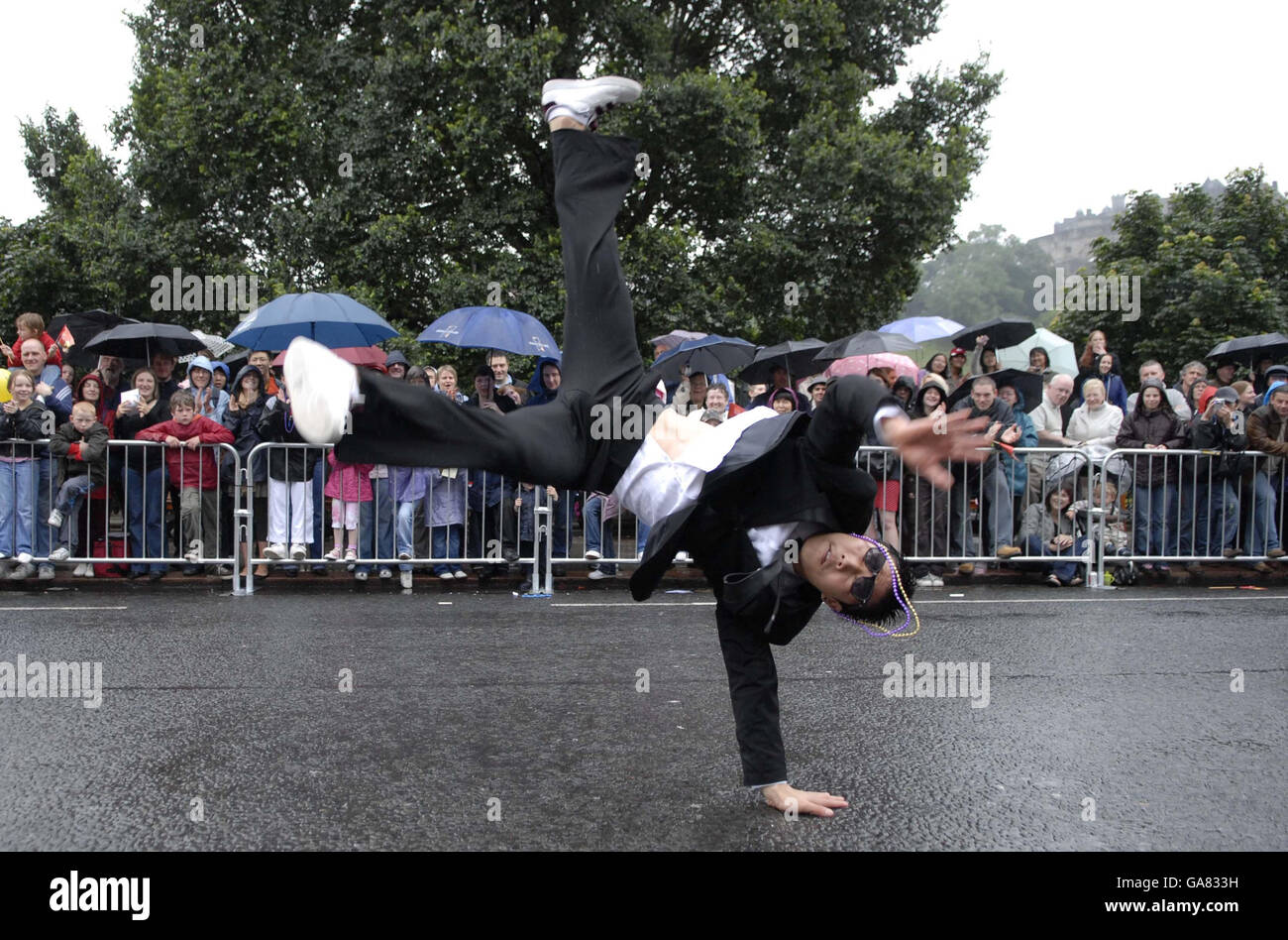 Un ballerino break si esibisce nella parata mentre gli spettatori sfidano la pioggia mentre l'annuale Edinburgh Festival Cavalcade si fa strada attraverso le strade della capitale scozzese. Foto Stock