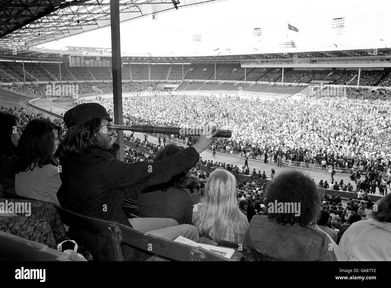 Musica - Concerto di rinascita Rock n Roll - Wembley. Un fan rock utilizza un telescopio per avvicinare l'azione di oggi. Foto Stock