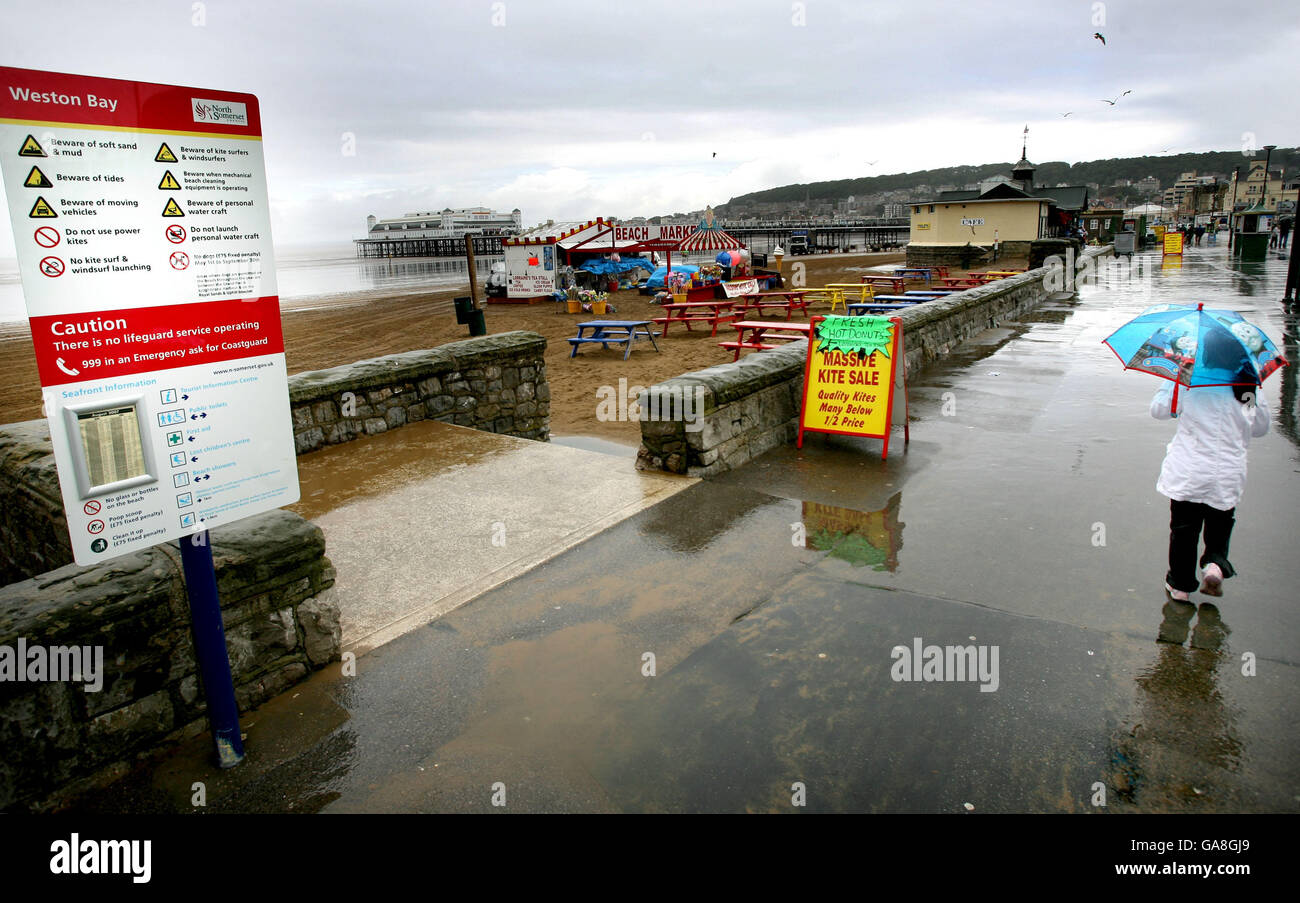 I vacanzieri passeggiano lungo il mare, facendo il meglio del maltempo al Weston-Super-Mare in Somerset. Foto Stock